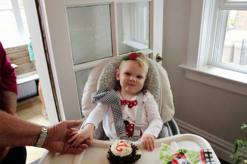 June's 2nd birthday in high chair with cake